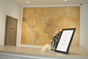 A reception desk with a large world map, a framed sign, and a door.