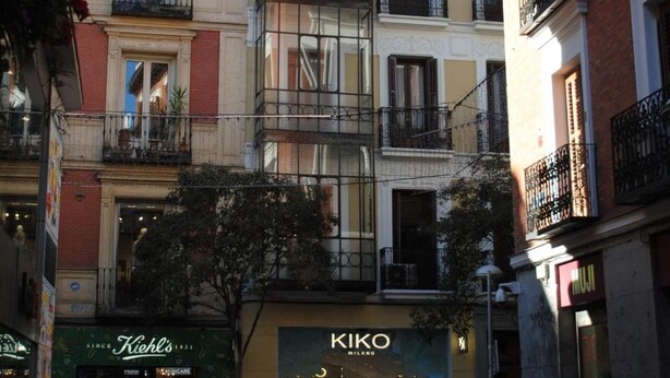Un edificio de varios pisos con fachada de vidrio, locales comerciales y balcones.