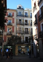 A multi-story building with a glass facade, storefronts, and balconies.