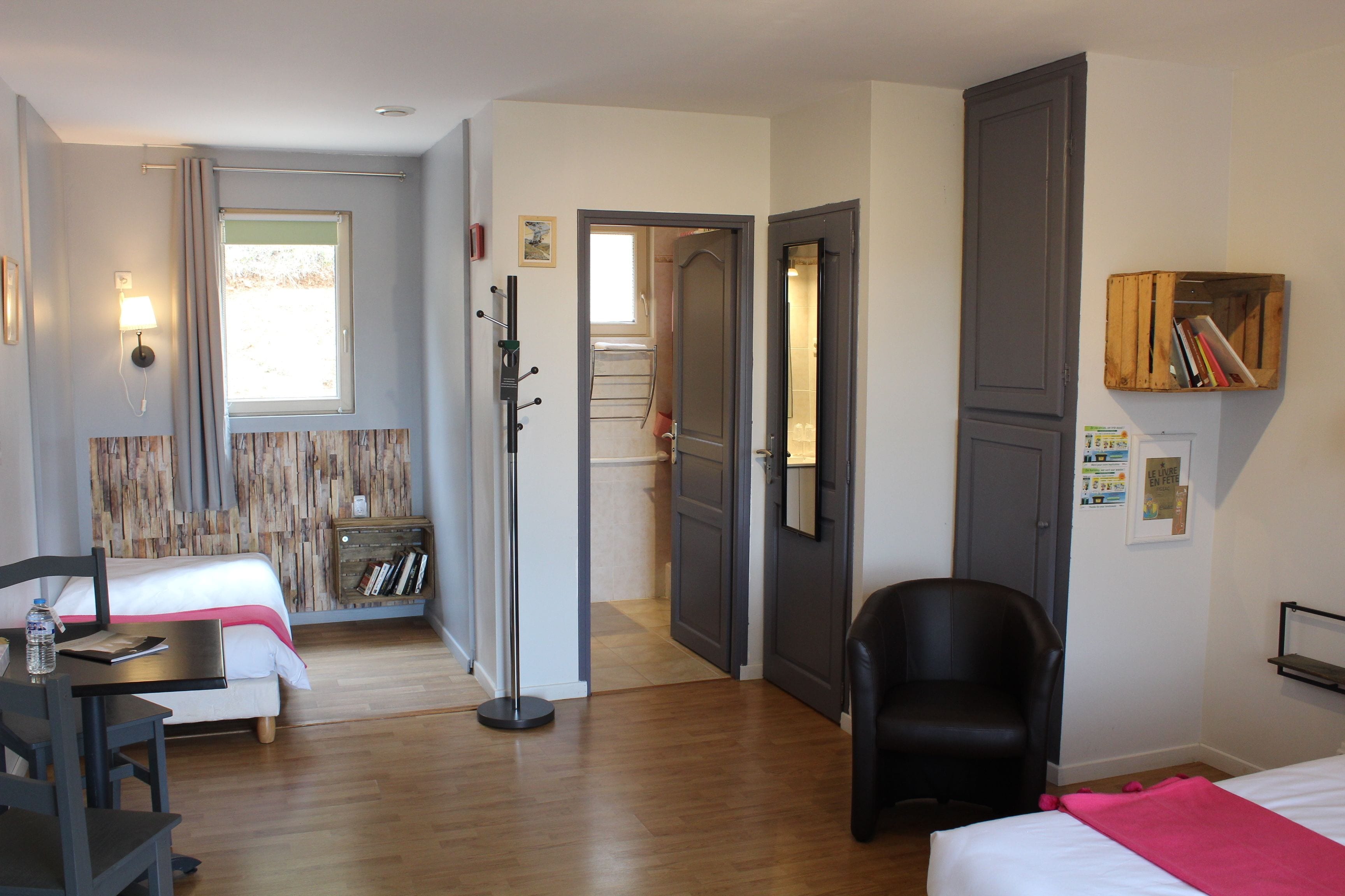 Una habitación de hotel con una cama, un escritorio con silla, un armario y una puerta que da al baño.