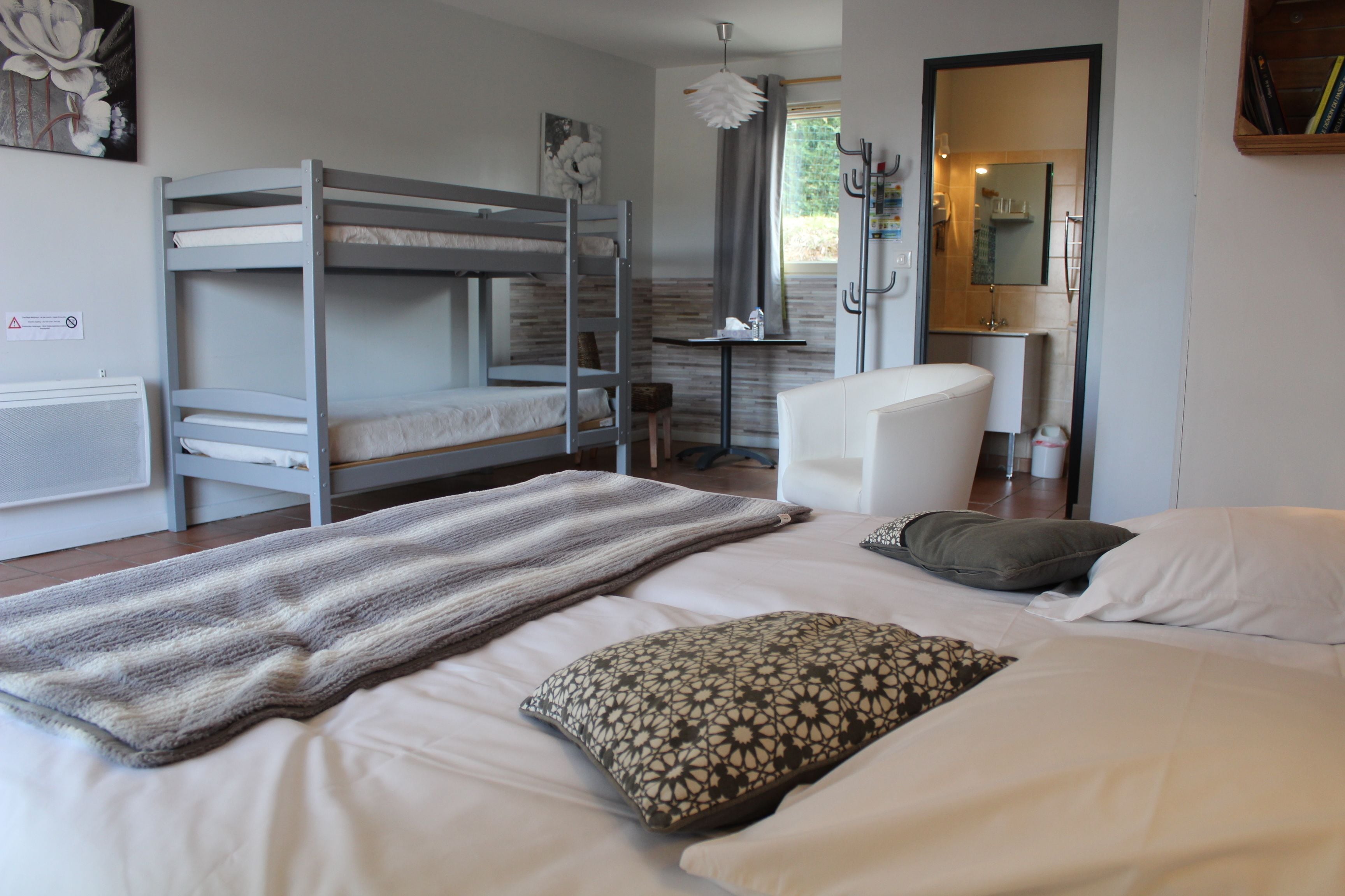 A bedroom with bunk beds, a desk, a chair, and a bathroom visible through an open door.