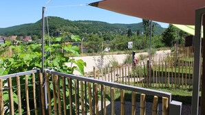Un balcón con vistas a un jardín y colinas lejanas.