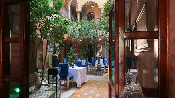 An indoor courtyard with tables and chairs, surrounded by plants and a patterned floor. - Riad Atlas Quatre & Spa (Marrakech)