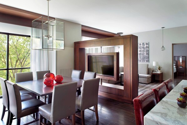A modern dining area with a large table, comfortable seating, a television, and a view of the outdoors. - Marriott Columbus OSU (Columbus)
