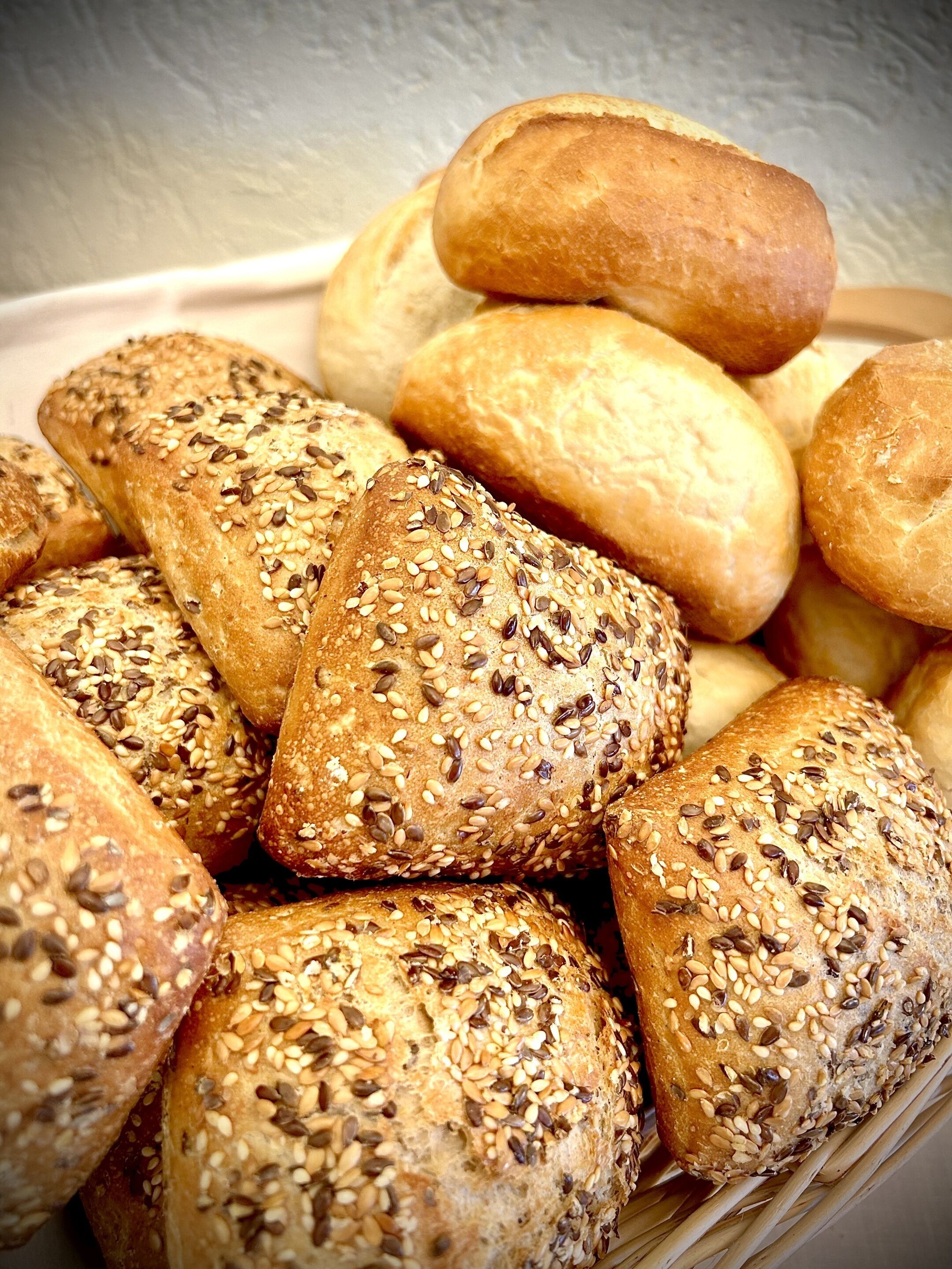 Ein Korb mit verschiedenen Brotsorten, darunter einige mit Saaten belegt.
