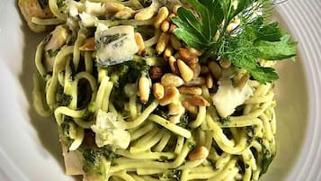 Een bord pasta met pesto, pijnboompitten en een garnering van peterselie.