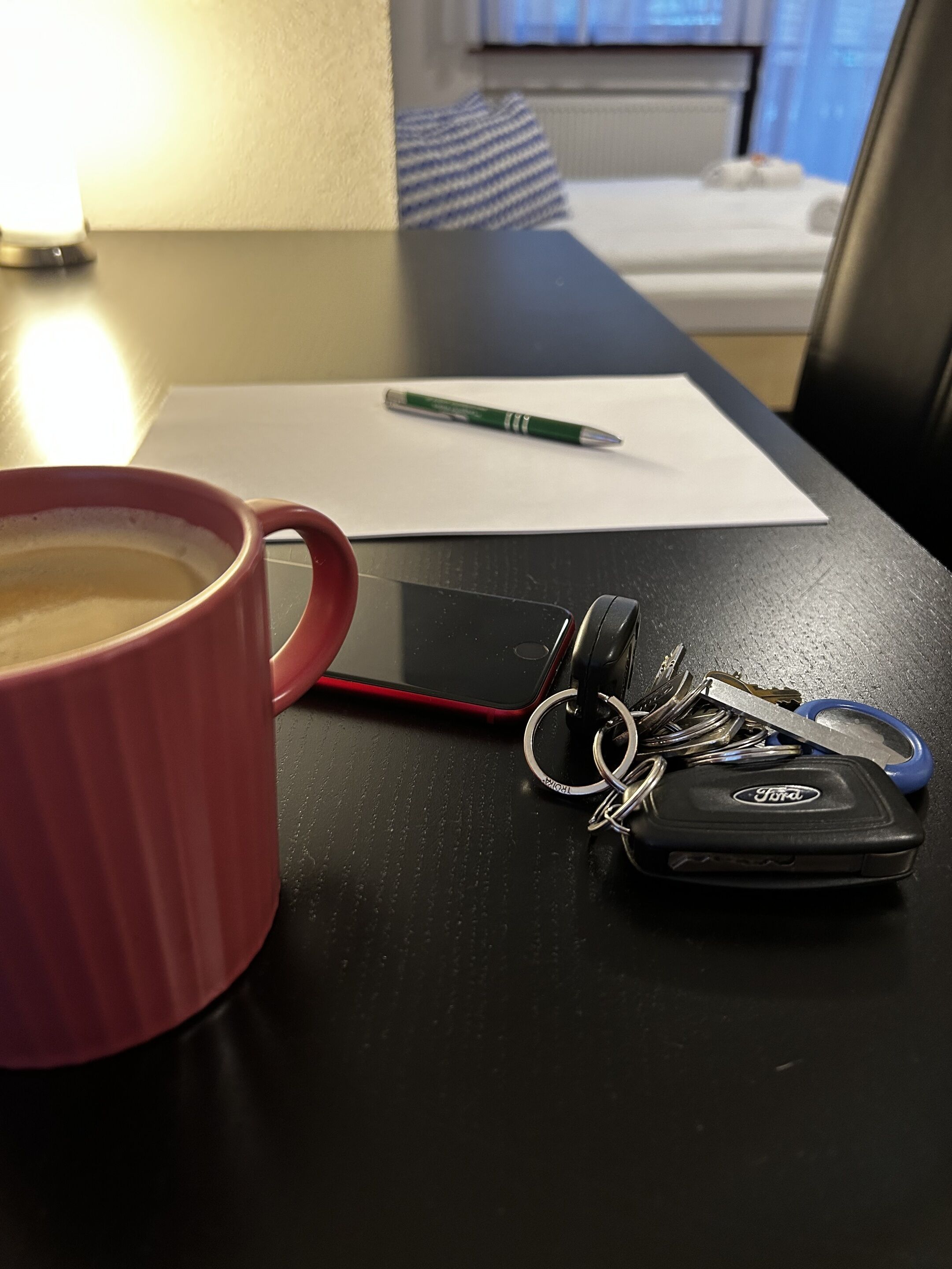 A table with a coffee mug, keys, a pen, and a notepad.