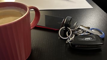 A table with a coffee mug, keys, a pen, and a notepad.
