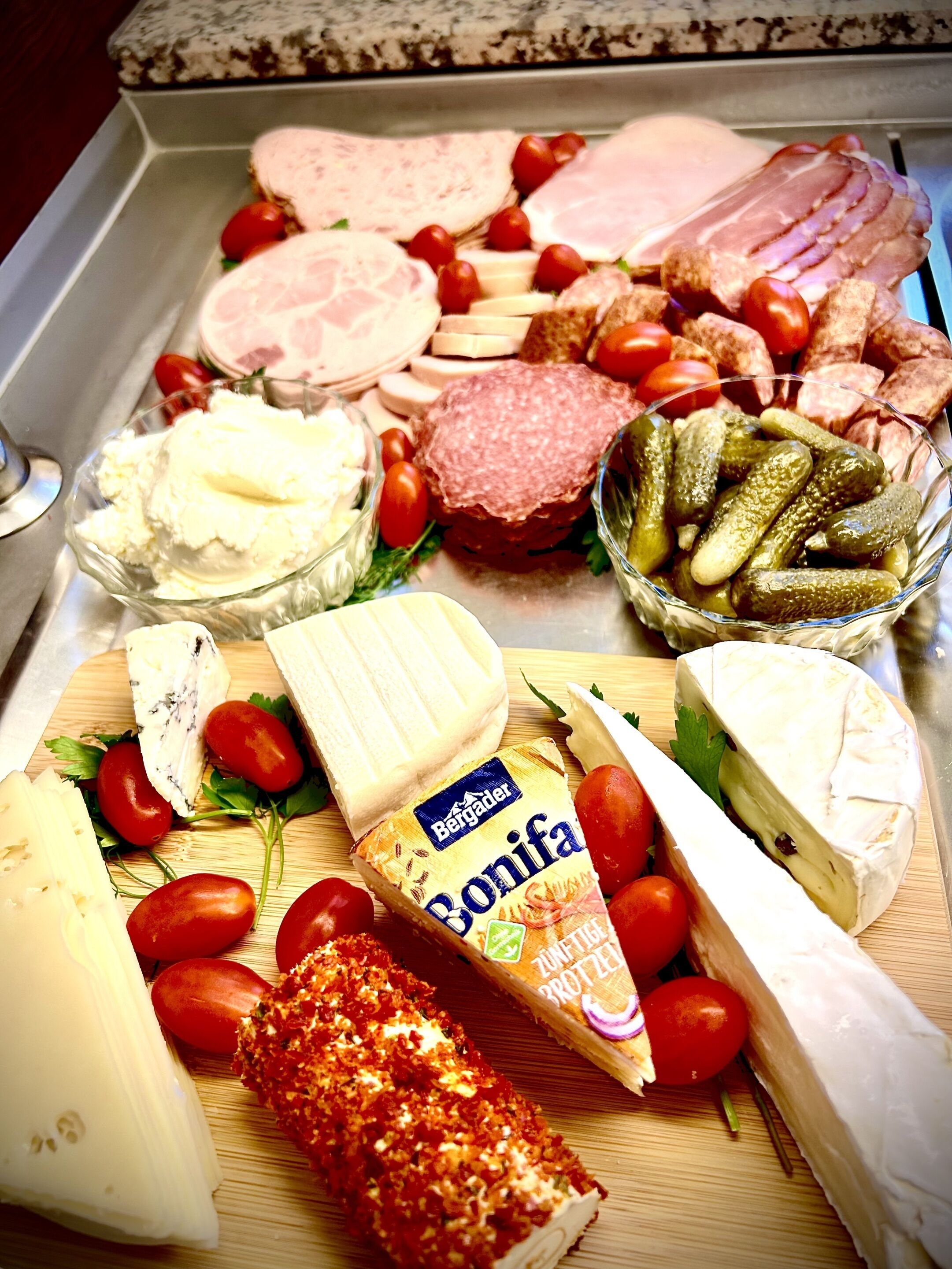 Eine Auswahl an Käse, Fleisch und eingelegten Gurken auf einem Holzbrett.