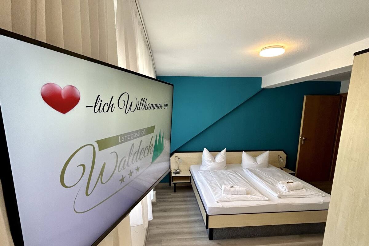 Une chambre d’hôtel équipée d’un lit, d’une table de chevet et d’un téléviseur fixé au mur qui affiche un message de bienvenue.