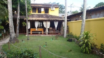 Traditional two-story building with a covered outdoor seating area and lush surroundings.