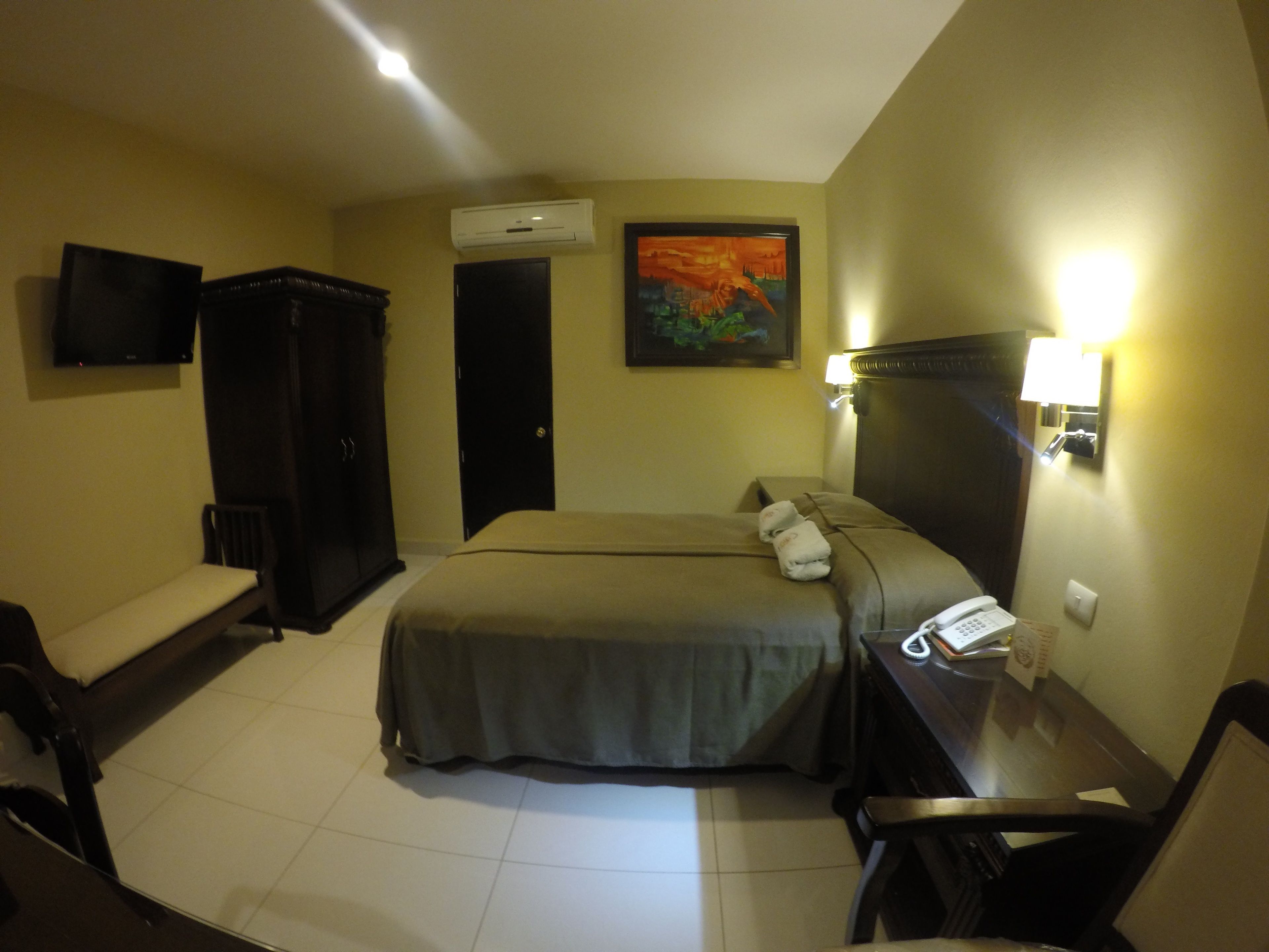 Habitación de hotel con dos camas, televisión, aire acondicionado, un cuadro y un escritorio con teléfono.