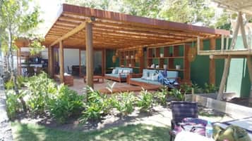 Un espace extérieur aménagé, abrité et doté de mobilier en bois, ainsi que d’un mur végétal.