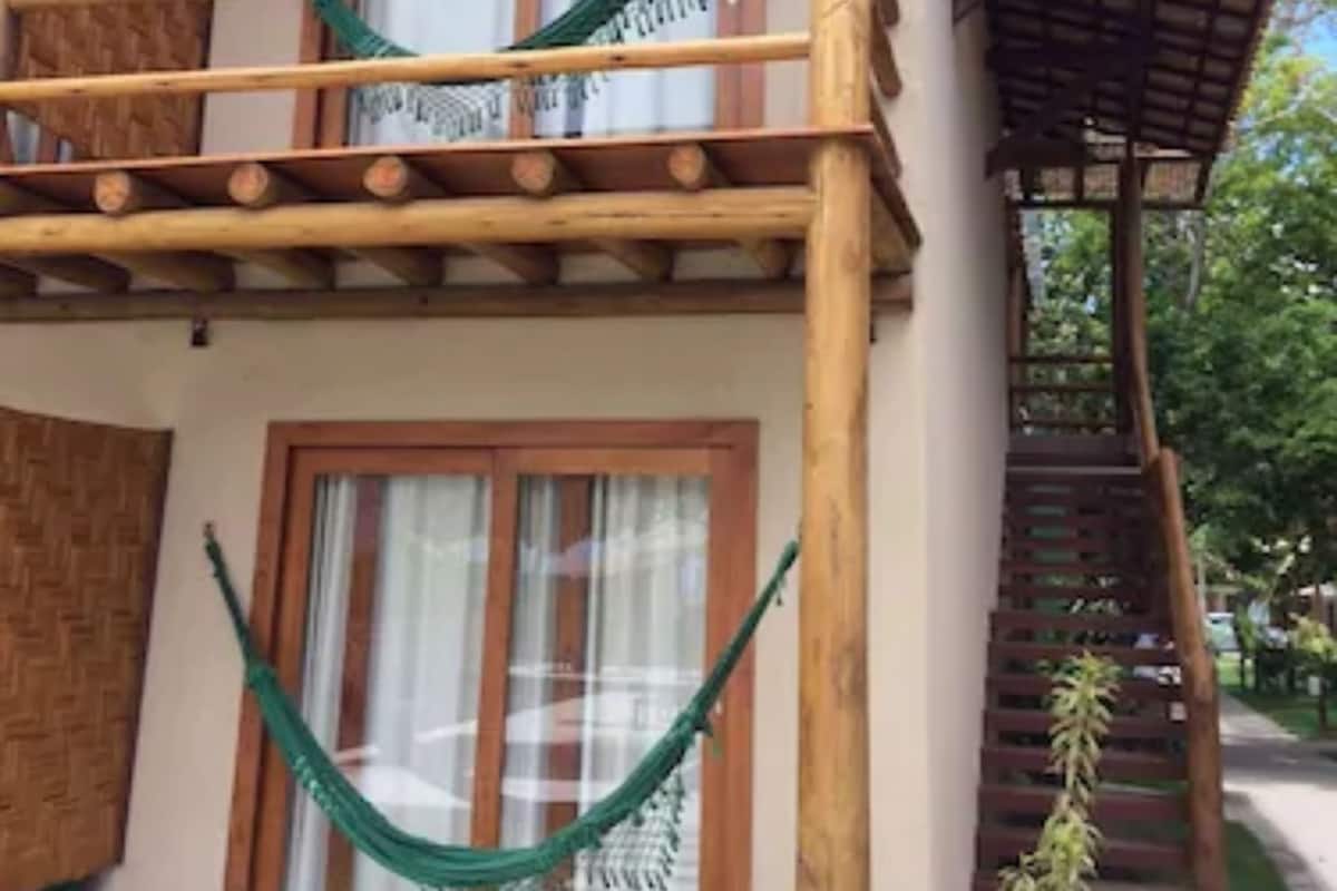 A two-story building with a wooden balcony and a hammock.