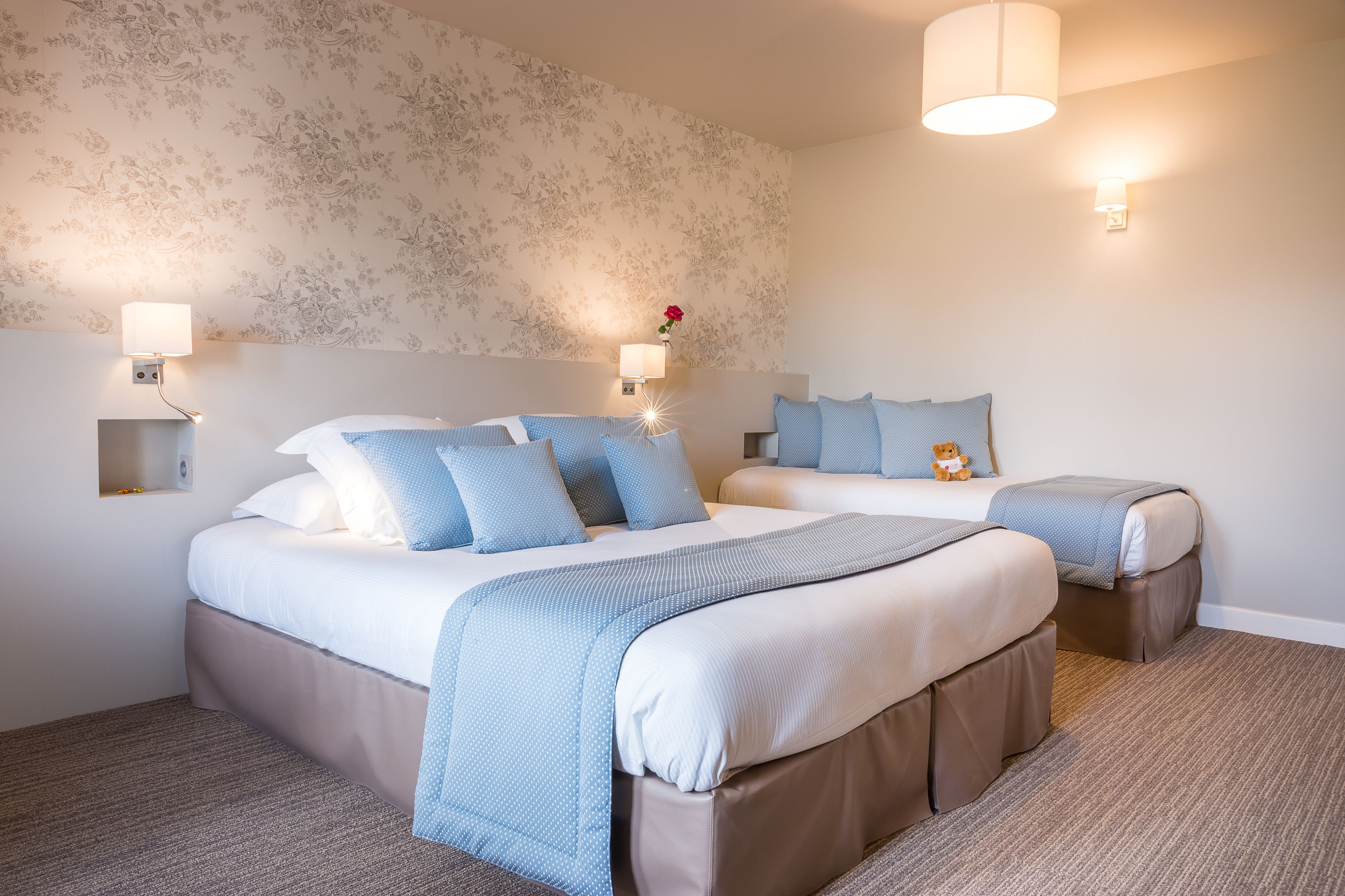 A hotel room with two beds, each with a headboard, a nightstand, and a lamp.