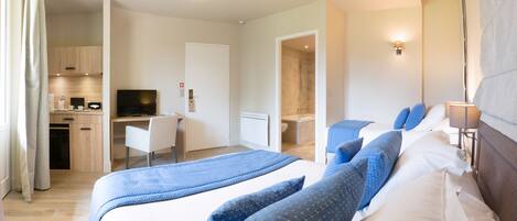 A hotel room with a bed, a desk, a TV, and a bathroom.