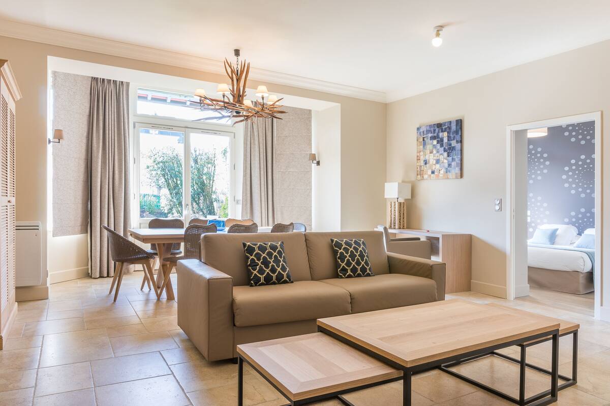 A modern living room with a sofa, coffee table, and dining area.