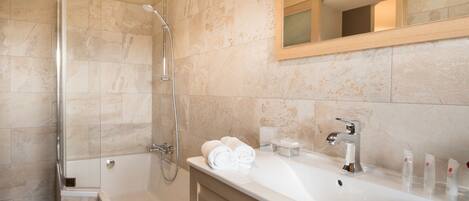 A modern bathroom with a glass-enclosed shower, a bathtub, and a vanity with a sink and mirror.