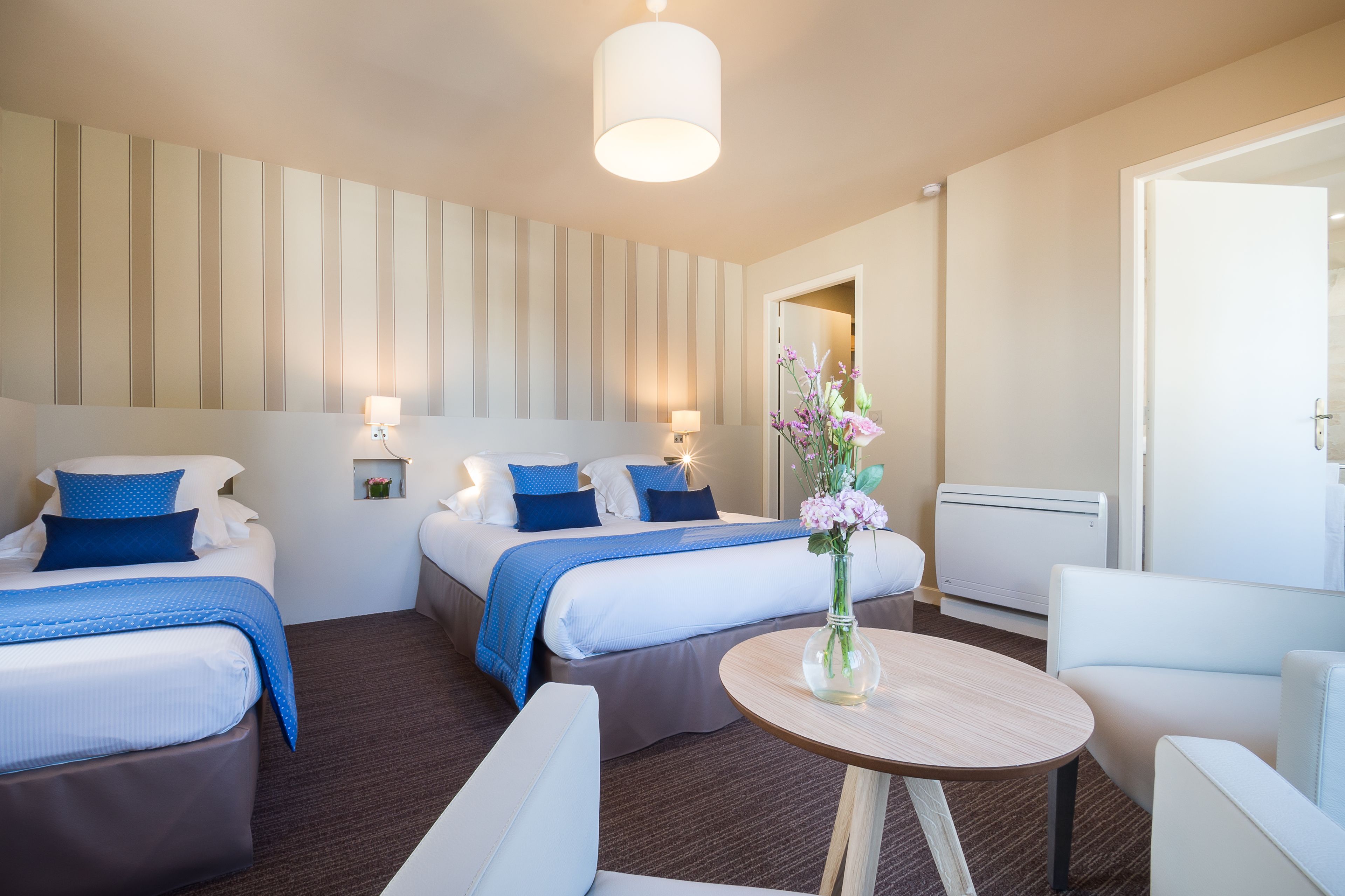 Une chambre d’hôtel avec deux lits, une table ronde et une chaise.