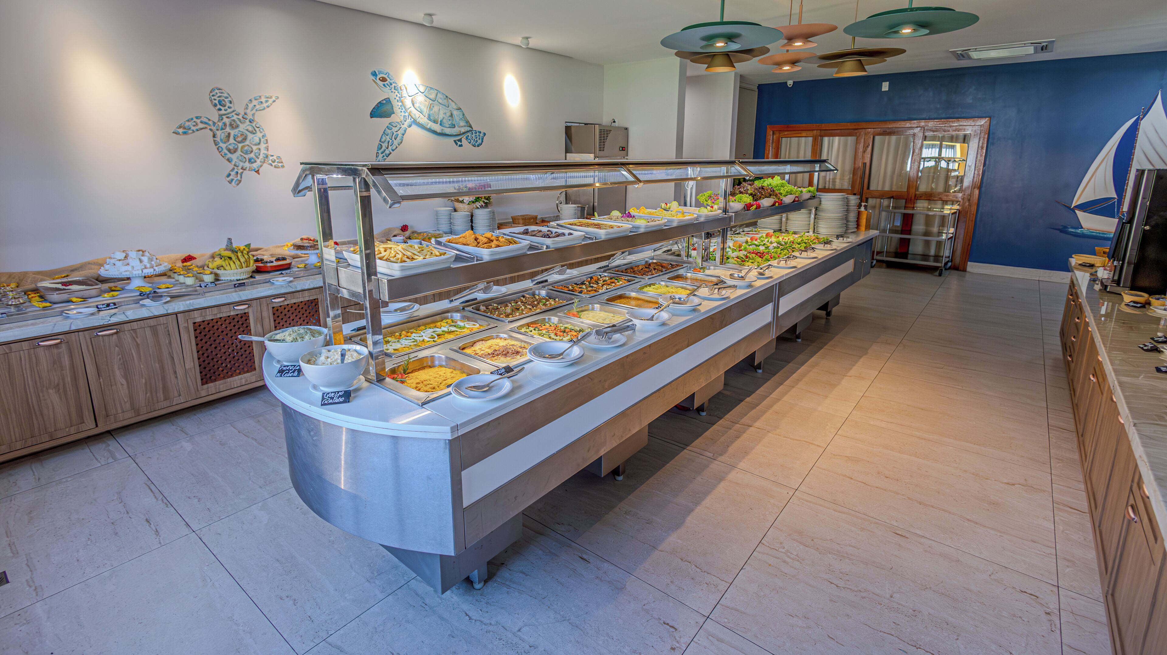 A buffet with multiple food stations, a wooden counter, and a blue wall with a mural.