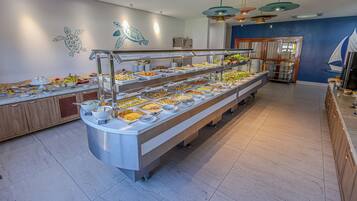 A buffet with multiple food stations, a wooden counter, and a blue wall with a mural.