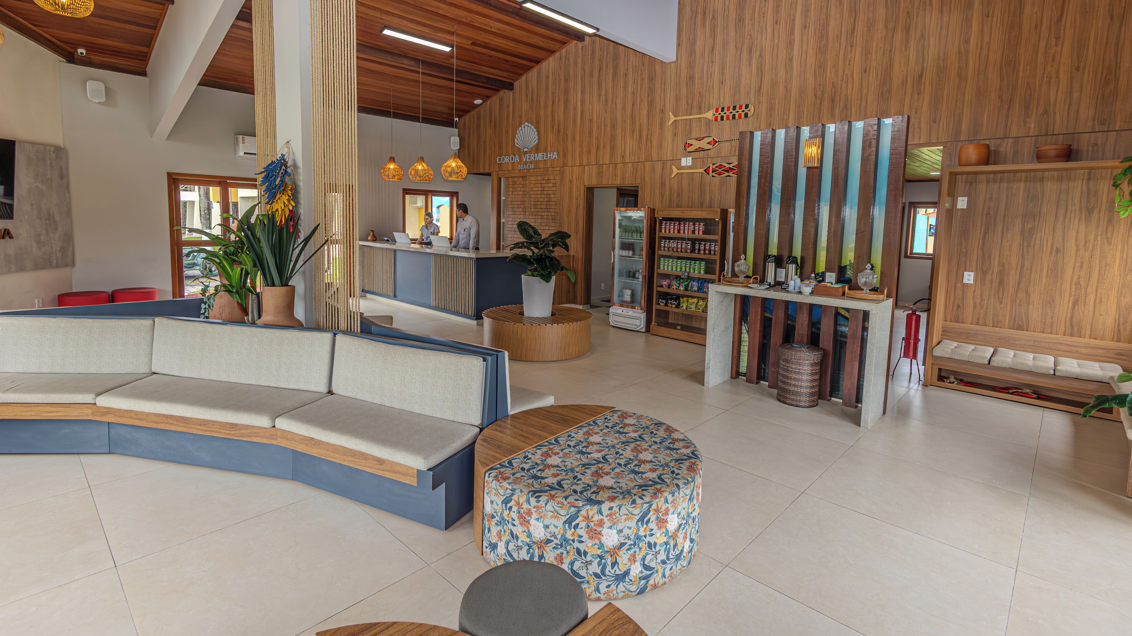 A modern hotel lobby with a curved seating area, a reception desk, and a bar area with wooden accents.