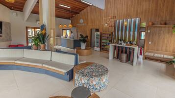 A modern hotel lobby with a curved seating area, a reception desk, and a bar area with wooden accents.