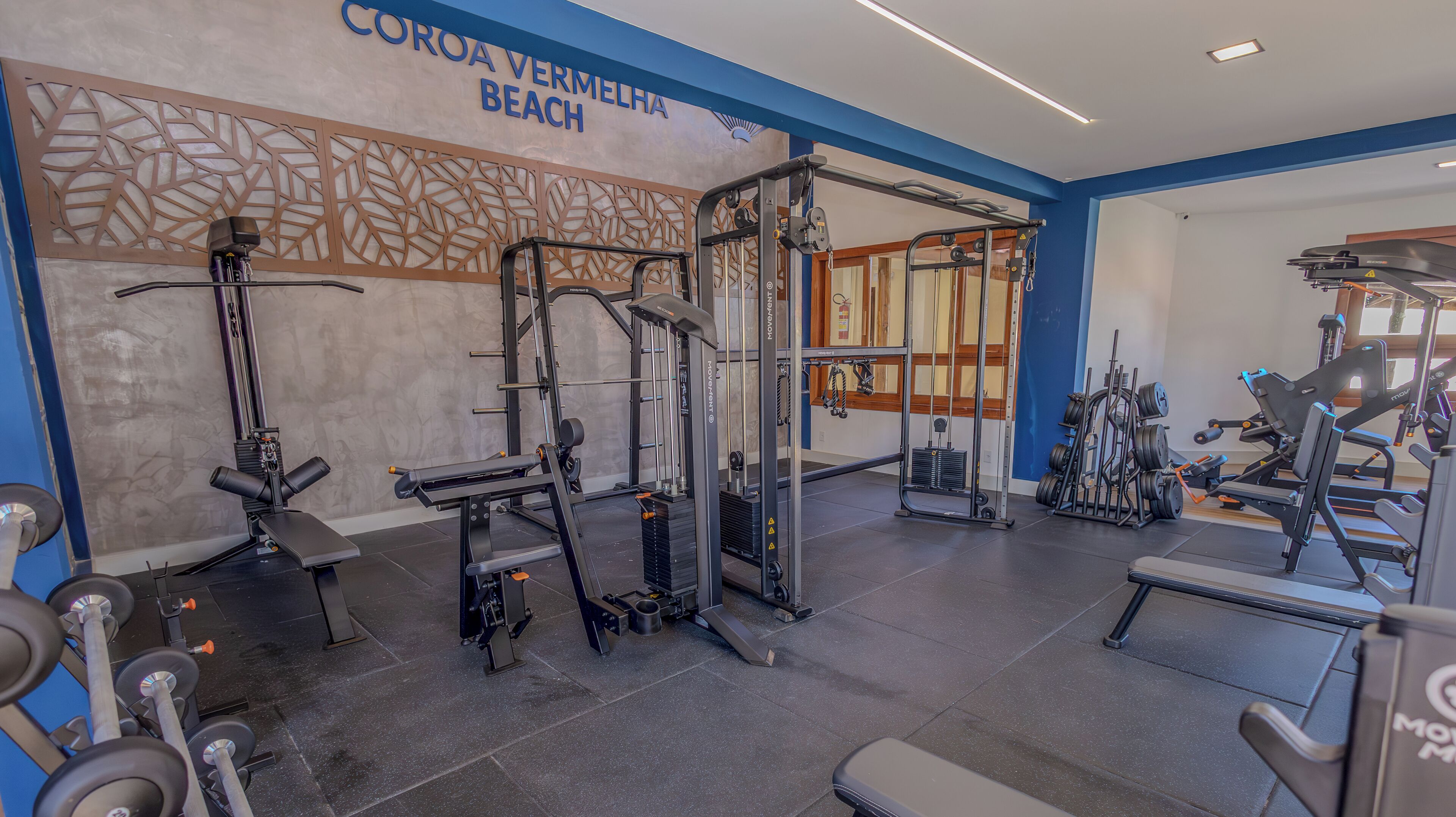 Et fitnesscenter med forskellig træningsudstyr, herunder styrkemaskiner og håndvægte.
