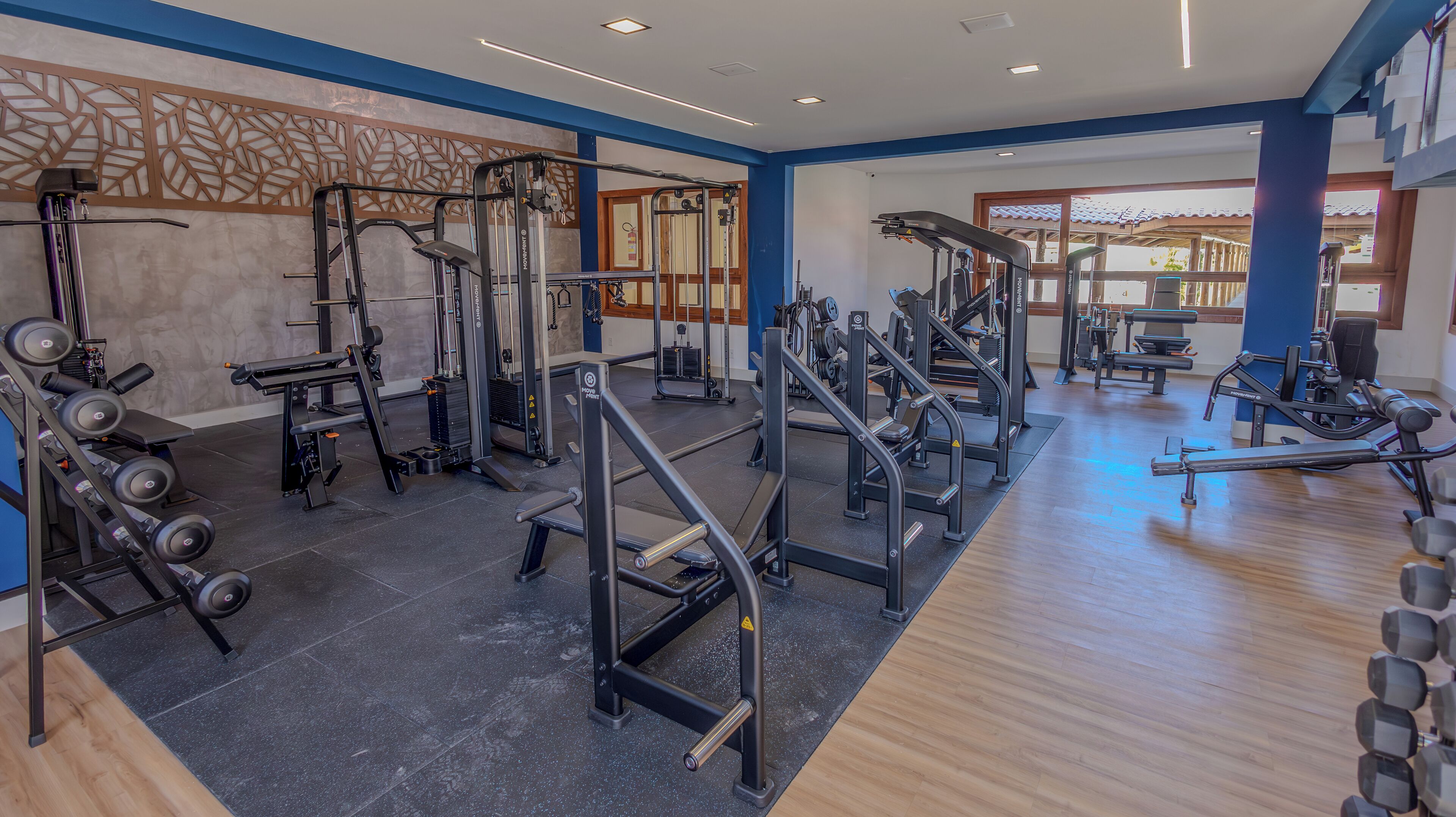 A gym with various exercise equipment, including weight machines, free weights, and cardio machines.