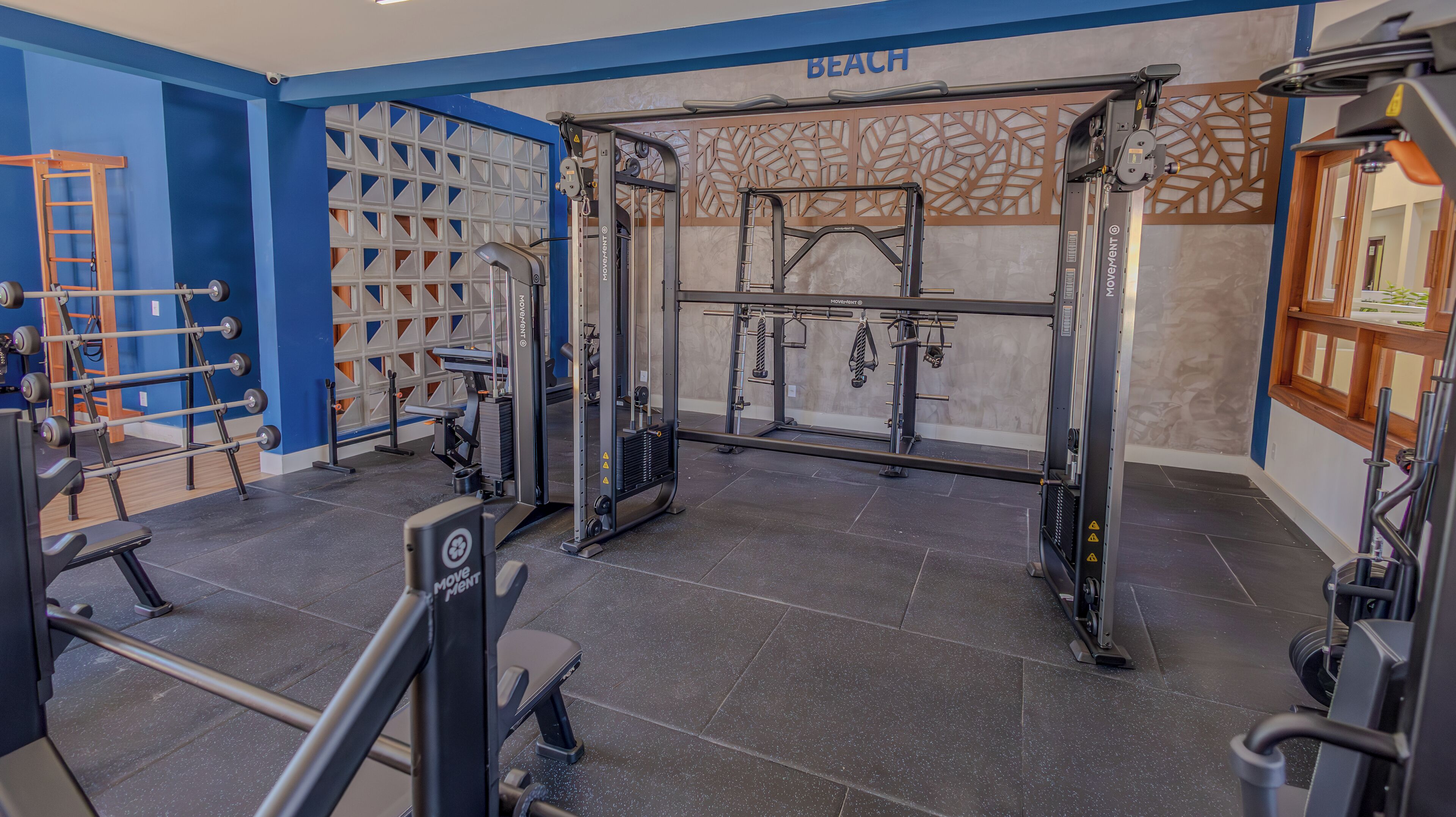 Un gimnasio con diferentes equipos de ejercicio, incluyendo una jaula para sentadillas y bancos de pesas.