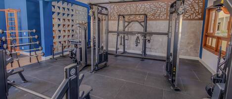 Un gimnasio con diferentes equipos de ejercicio, incluyendo una jaula para sentadillas y bancos de pesas.