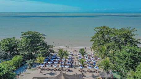 En la playa, arena blanca, sillas reclinables de playa, sombrillas