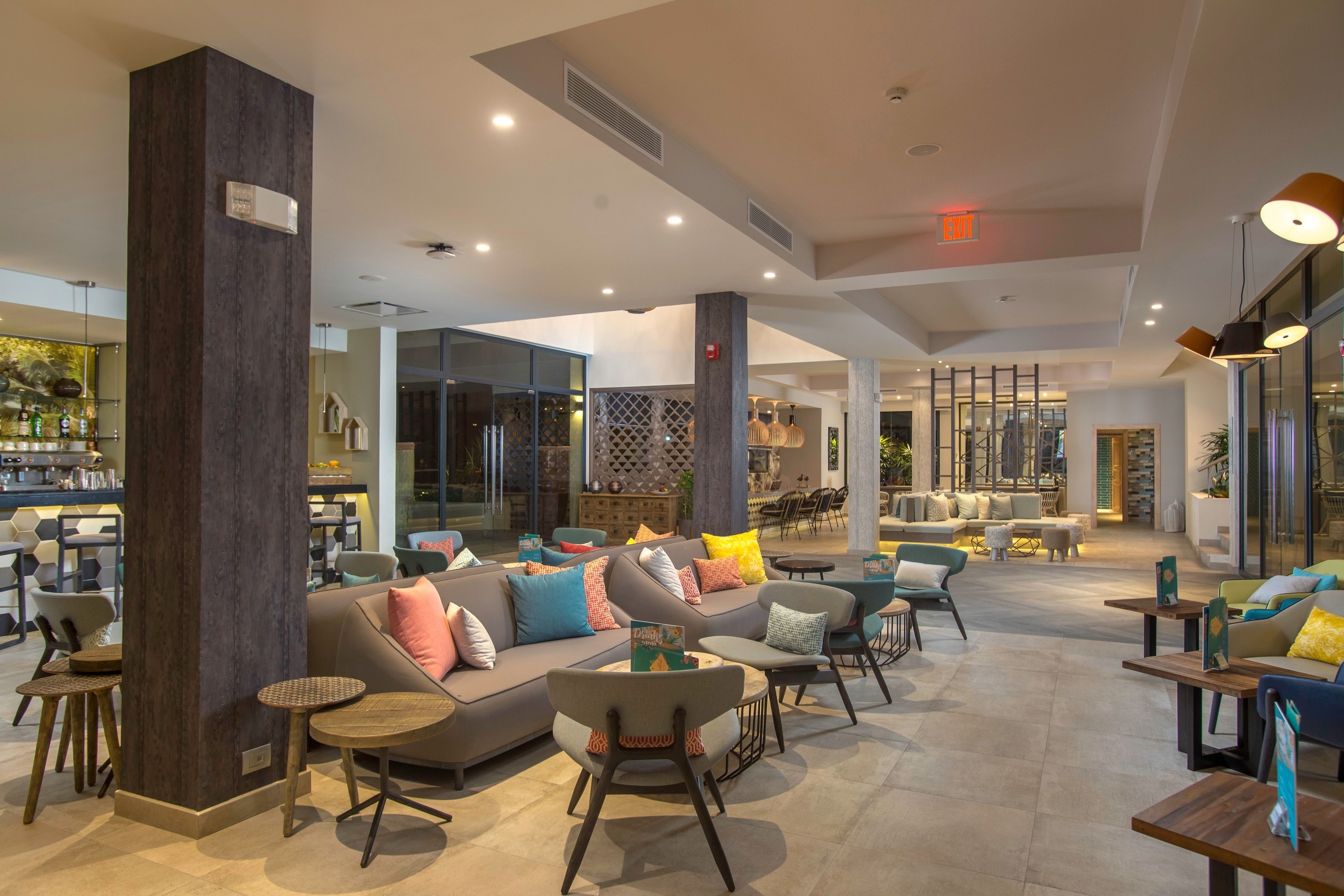 A spacious lobby with a modern design, featuring a large sofa, multiple seating areas, and a bar area.