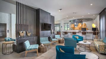 A modern lounge area with seating arrangements, a bar, and a television screen.