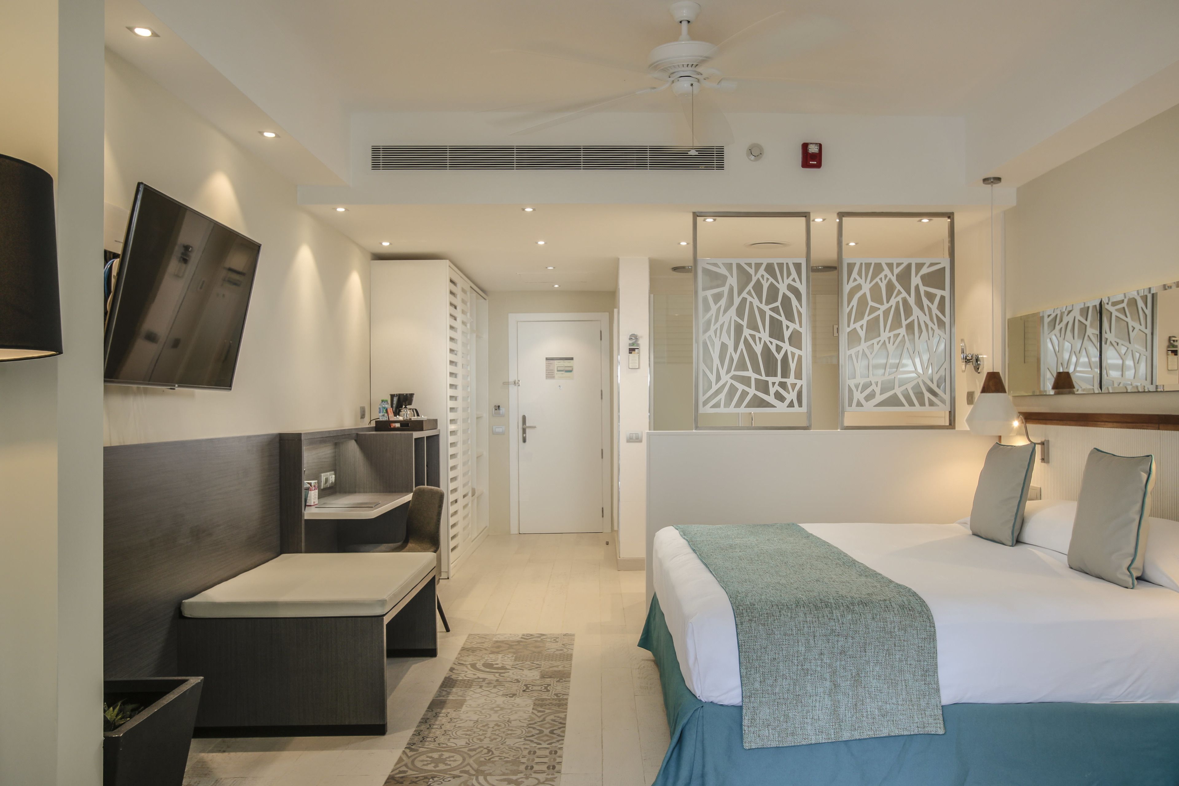 A modern hotel room with a bed, bedside table, and a TV mounted on the wall.