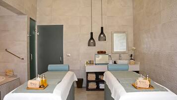 A hotel room with two beds, a bathroom, and a small sitting area.