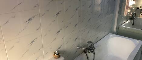 A bathroom with a white bathtub, a toilet, and a bidet.