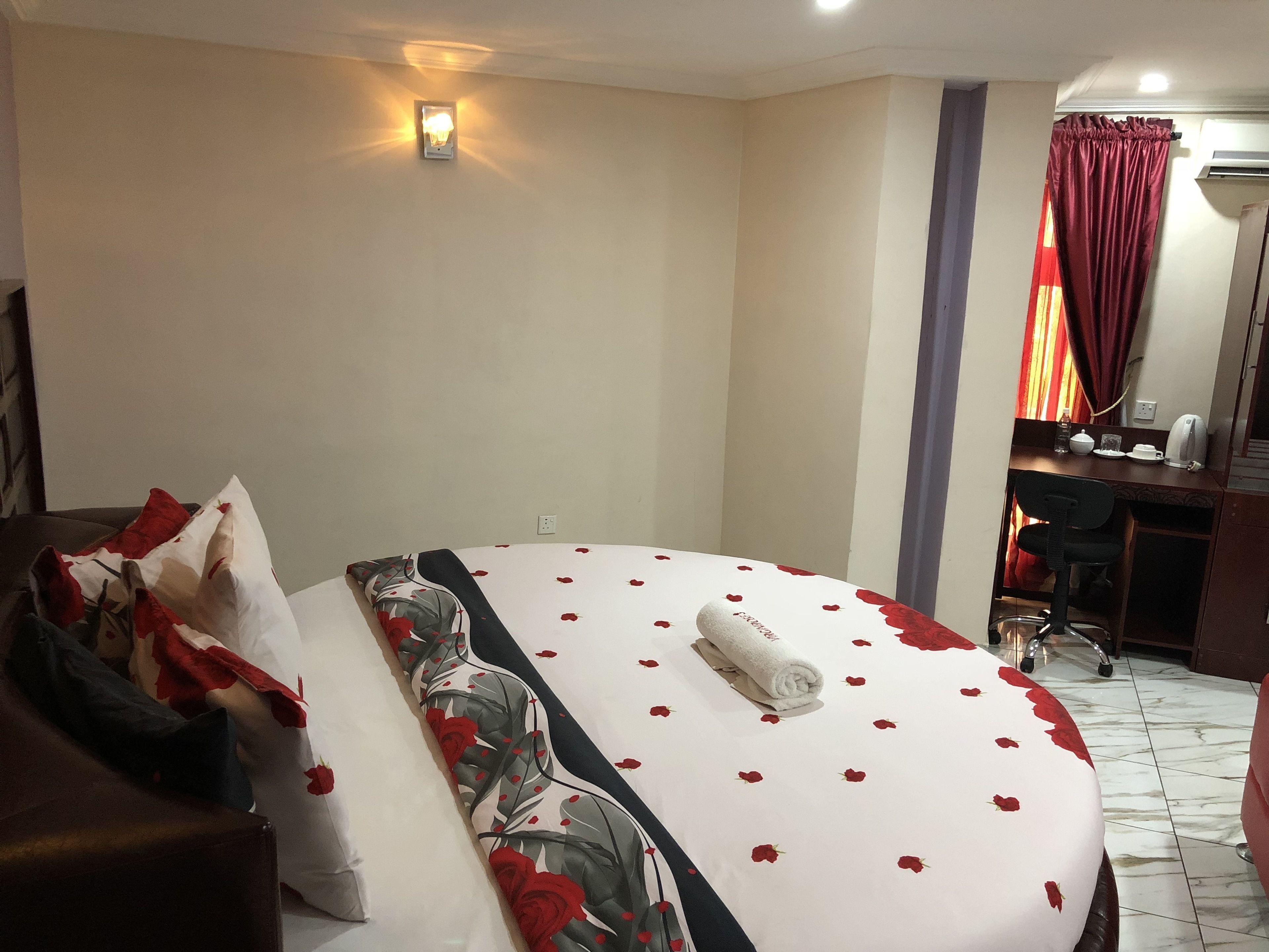 Habitación de hotel con cama, escritorio y silla. Hay una lámpara de pared sobre la cama.