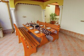 An outdoor dining area with a wooden table set for six, surrounded by benches. - Villa in Croatia with Pool near Beach (Dramalj)