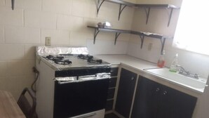A compact kitchen with a stove, cabinets, and a sink. - Park Motel (North Platte)