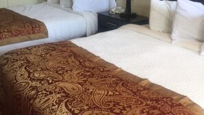 A hotel room with two beds, a nightstand with a lamp, and a patterned bedspread. - Park Motel (North Platte)