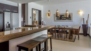 Una cocina moderna con una isla central, electrodomésticos de acero inoxidable y una zona de comedor con sillas y mesa de madera.