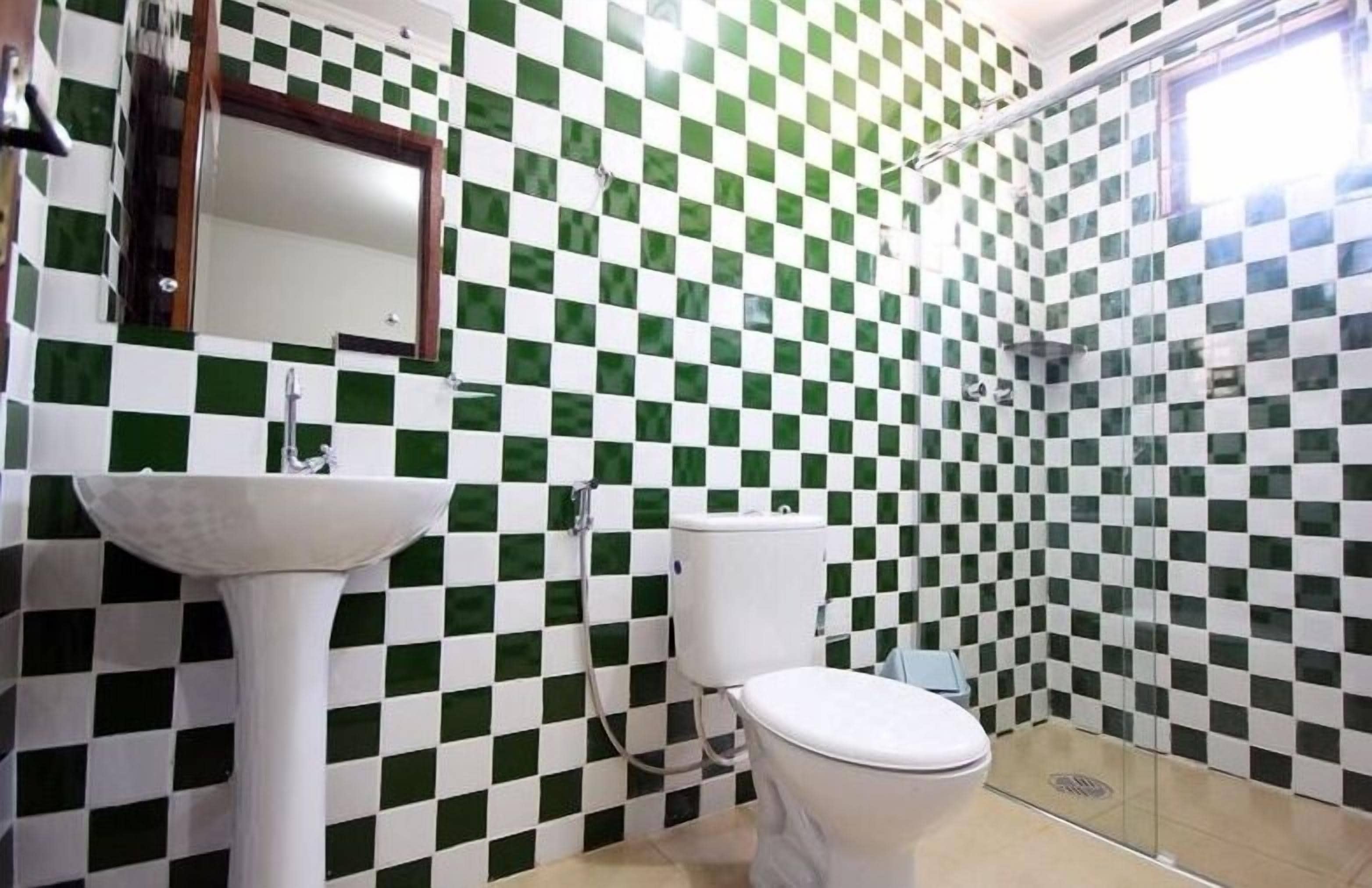 Une salle de bain avec un mur recouvert de carreaux à motifs géométriques, un lavabo, des toilettes et un espace douche.