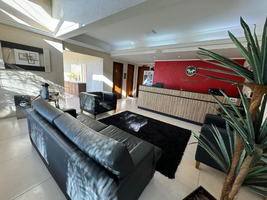 A hotel lobby with a reception desk, a black leather sofa, a coffee table, and a large plant.