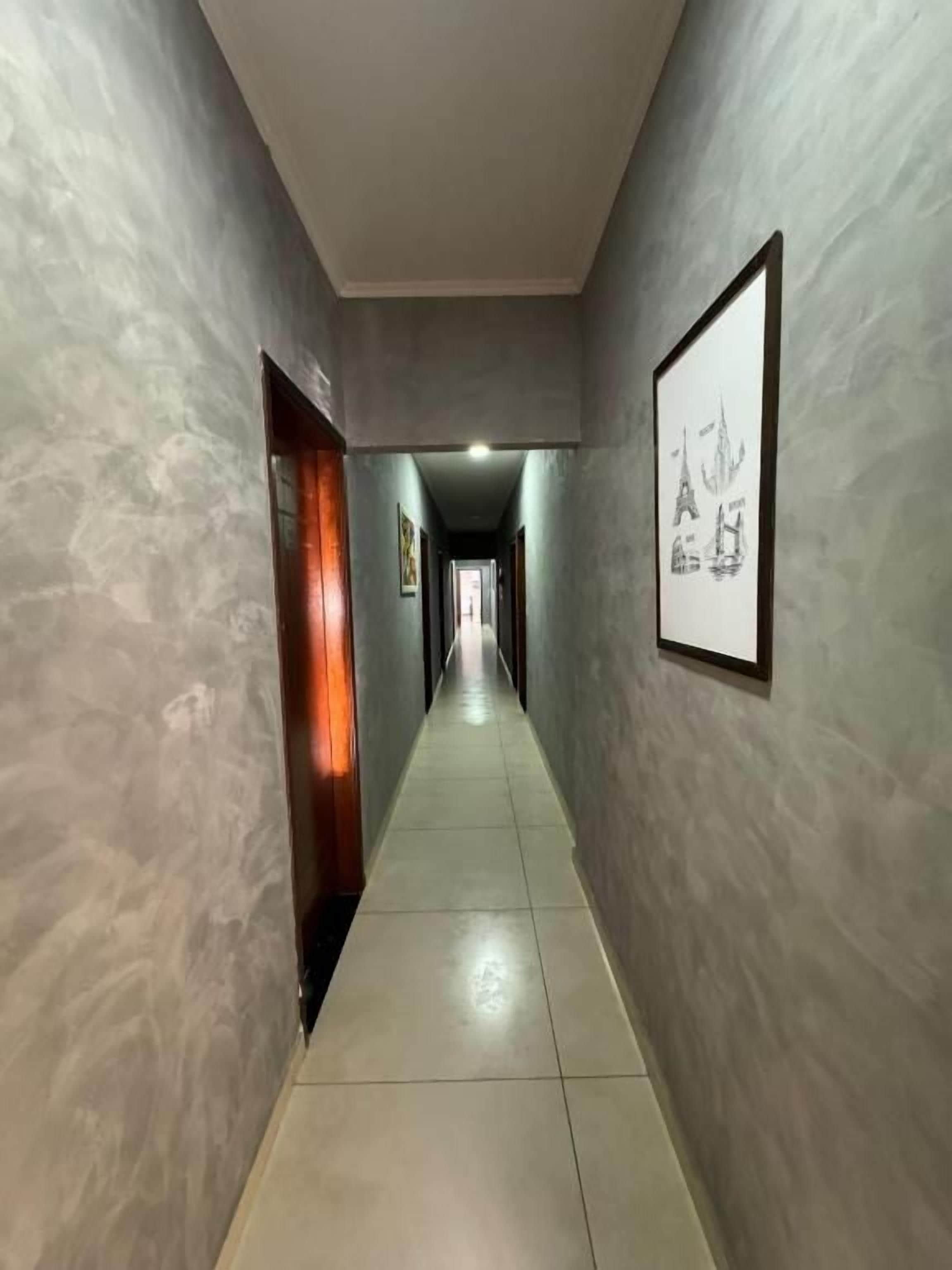 Un couloir doté d’un sol carrelé et de murs à texture, qui mène à une porte au fond.