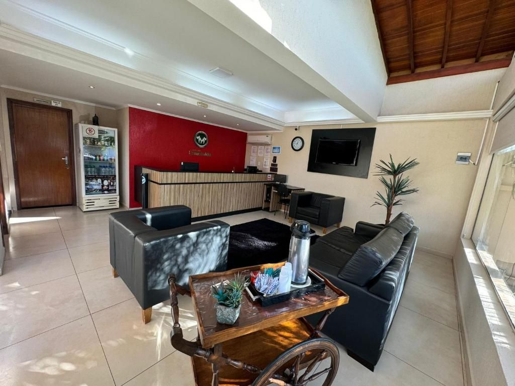 Un vestíbulo de hotel con mostrador de recepción, zona de estar y televisor montado en la pared.