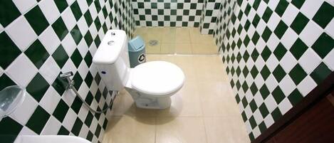 A bathroom with a checkered tile pattern, a white toilet, a bidet, and a urinal.