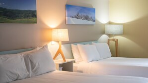 Ein Hotelzimmer mit zwei Betten, einem Nachttisch, einer Lampe und einem Bild an der Wand.