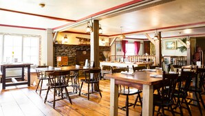 Ein Restaurant mit Holztischen und -stühlen, Steinwänden und hängenden Lampen.