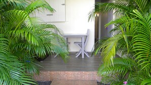 A patio area with a table and chairs, surrounded by lush greenery and a brick border. - Domaine de May (Saint-François)